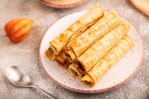 Waffles with caramel on brown concrete background and orange linen textile, cup of coffee, side