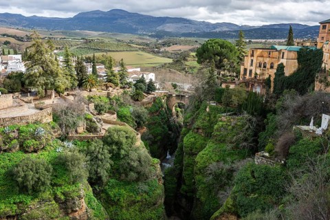 High angle panoramic view of the lush El Tajo gorge in Ronda with white houses and historic