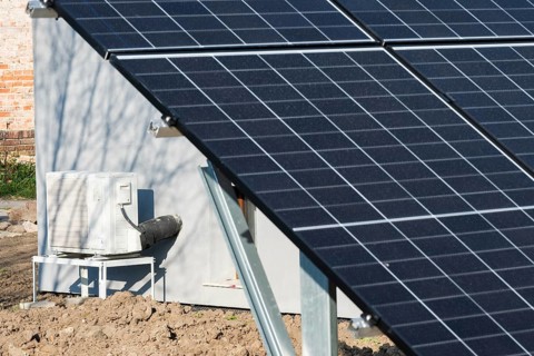 A ground-mounted solar photovoltaic panel array installed in front of a building with an outdoor