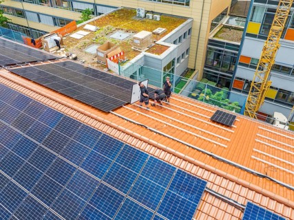 Assembly of solar modules by workers on urban roof, new PV system at Heinrich-Immanuel-Perrot