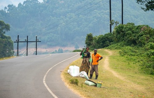 People with bags waiting on the side of the road, street scene in rural Uganda, Western Region,