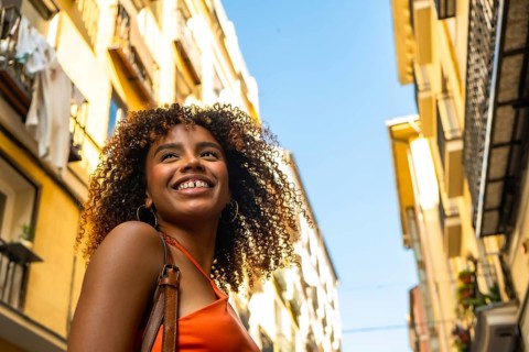 Young black woman with curly hair exploring a city, enjoying travel and urban life, smiling with