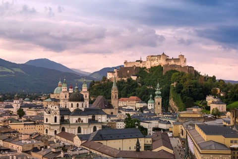 An atmospheric view of Salzburg with the Hohensalzburg Fortress and Alpine panorama in the evening