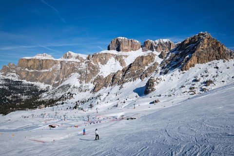 View of a ski resort piste with people skiing in Dolomites in Italy. Ski area Belvedere. Canazei,