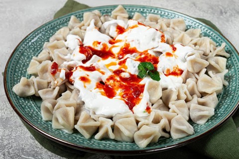 The dish features a generous serving of Turkish dumplings topped with velvety yogurt and a drizzle
