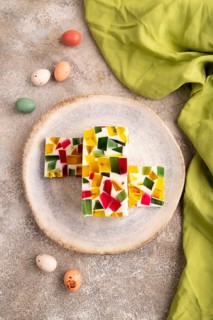 Colored Fruit and milk jelly on brown concrete background and green linen textile, top view, flat