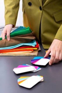 A professional image consultant examines a range of colorful fabric samples and color swatches on a