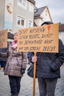 People holding placards at a demonstration with political messages in an urban environment, Against