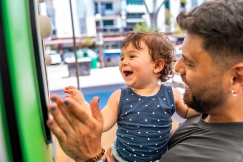 Father holding his adorable baby son while playing enthusiastically at a playground, with the child