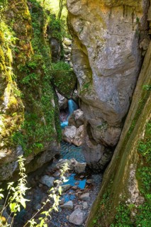 Turquoise water flowing through tolmin gorges, a scenic canyon with mossy rock walls in triglav