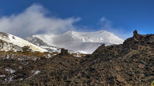Black wall of lava rubble, blue sky, white clouds, snow-capped peaks, Etna, volcano, Eastern