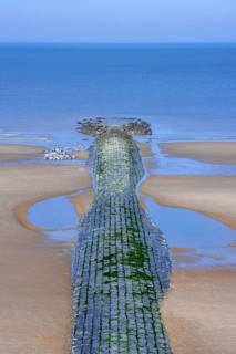 Tide pools along stone groyne, breakwater to minimize beach sand erosion along North Sea coast at