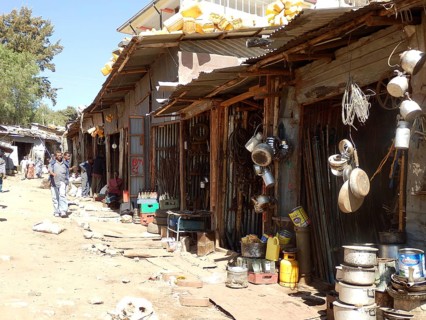 Street with huts, shops and household items on display in sunny weather, Harar, Ethiopia