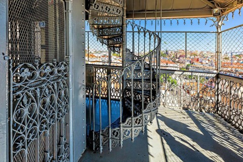Ornate wrought iron balcony overlooking a sunny cityscape with clear blue sky, Elevador De Santa