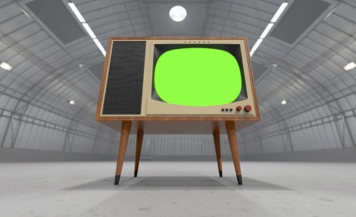 Vintage television with chroma green screen resting in the middle of an empty warehouse