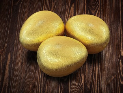 Three golden Easter eggs isolated on wooden background