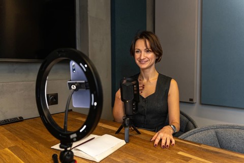 Smiling female content creator gesturing during video recording with professional setup