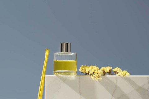 Elegant glass diffuser filled with lemon-scented liquid, accompanied by yellow sticks and delicate