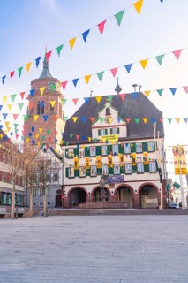 Historic façade with colourful flags in the morning light in a busy town, Fasnet, Weil der Stadt,
