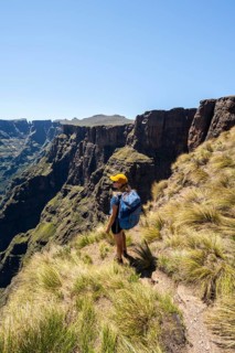 Young hiker looking at the impressive mountains and cliffs of the Drakensberg Mountains, hiking
