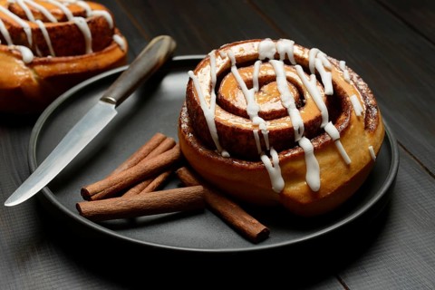 Cinnamon roll on plate and cinnamon sticks