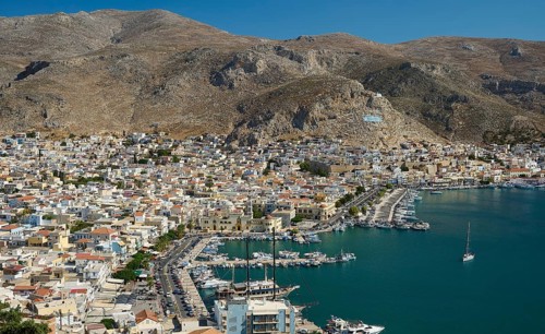 Coastal town with harbor, lined with boats and surrounded by impressive mountain scenery, Pothia,