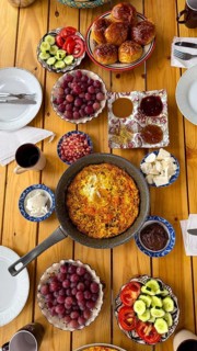 Wooden table laden with a colorful and healthy mediterranean style breakfast, featuring a large
