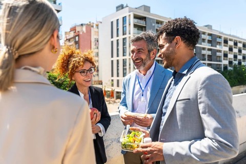 Business professionals networking and smiling over lunch on a sunny urban rooftop, sharing ideas,