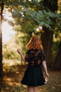 A woman with red hair enjoys the autumn sunlight filtering through trees in a serene Quebec forest.