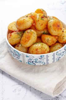 Baked new potatoes, with butter and dill, on a white plate, at home, no people