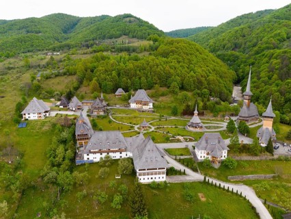 Panoramic view of a monastery with wooden churches and green hills, aerial view, Bârsana monastery,