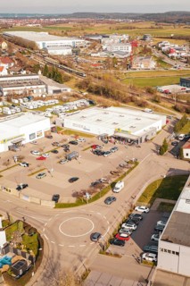 Aerial view of a shopping mall with lots of cars in the parking lot in an urban industrial area,