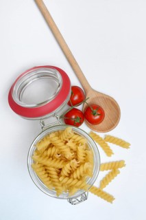 Pasta, 'Fusili' variety in glass container with cooking spoon