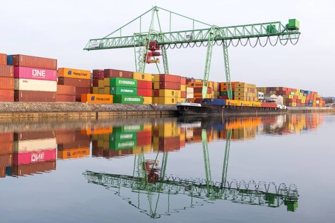 Colourful containers and a green crane are reflected in calm harbor water, Stuttgart,