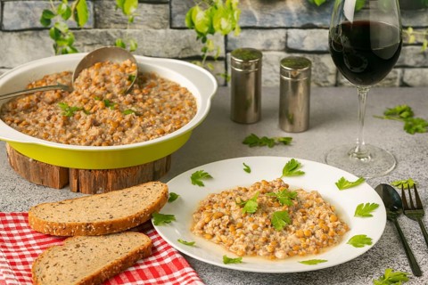 Lentils with bacon in a bowl and on a plate with bread and wine glass