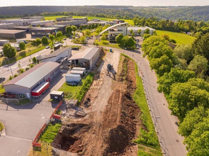 Earthworks along a road with green surroundings and urban development, Parkhaus Bau, Calw, Germany