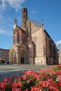 Frauenkirche church on Hauptmarkt in Nuremberg, Germany, seen above red flowers with Gothic