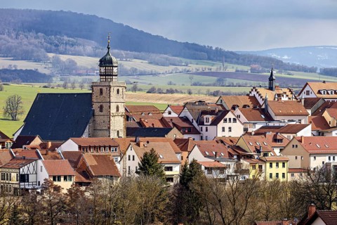 Historic town with characteristic tower and red roofs, surrounded by hills, the skyline of Geisa in