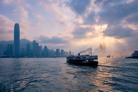 Hong Kong skyline cityscape downtown skyscrapers over Victoria Harbour on sunset with tourist ferry