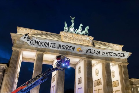 Fire ladder in front of a banner For Democracy in Syria / Defend Rojava hanging at the Brandenburg