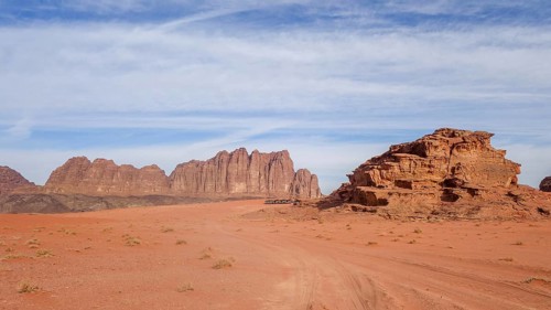 Expansive view of Wadi Rum's sandy desert and towering rock formations under a clear blue sky in
