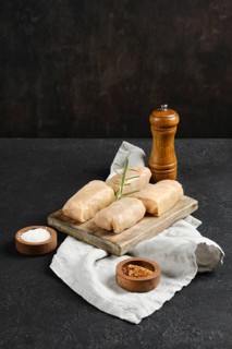 Cabbage spring rolls stuffed with meat on a wooden cutting board with spices and a sprig of