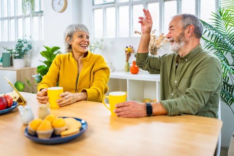 Happy senior caucasian couple talking enjoying breakfast together at home