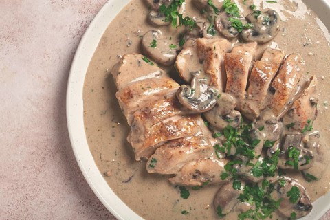 Chicken in cream sauce with mushrooms, on a plate, no people