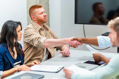 Business partners engaging in a handshake after finalizing a contract during an office meeting,