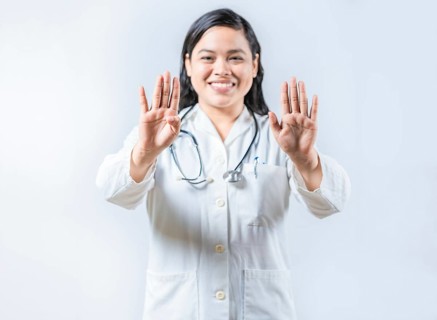 Asian female doctor counting number 9 on isolated background. Asian healthcare worker counting