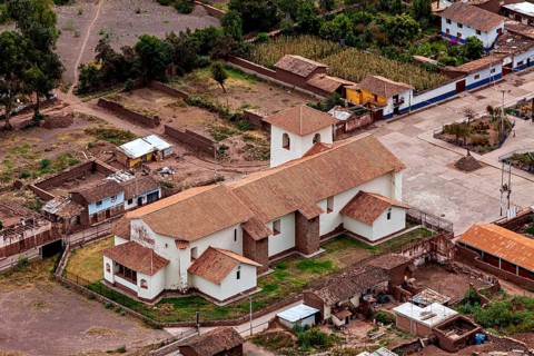 Aerial view of a traditional church with red roofs in a small village in Peru surrounded by