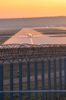 Airplane rolling at airport, barbed wire in foreground, Stuttgart Airport, Germany