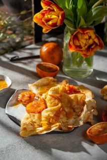 A plate of crepes Suzette garnished with caramelized slices of blood orange in a rich butter sugar