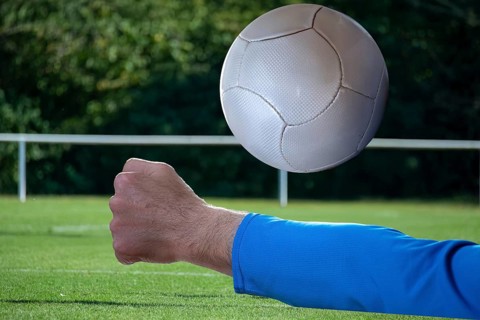 (Photomontage) Fistball symbol image: close-up of a fistball player on the ball